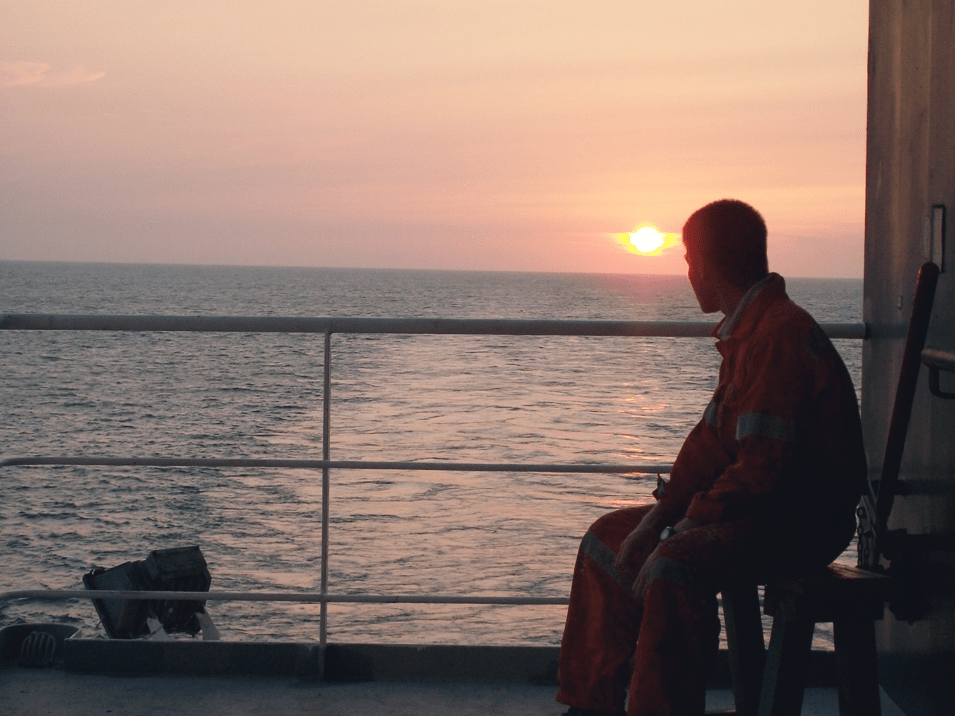 Man sitting on a ship, looking out to sea